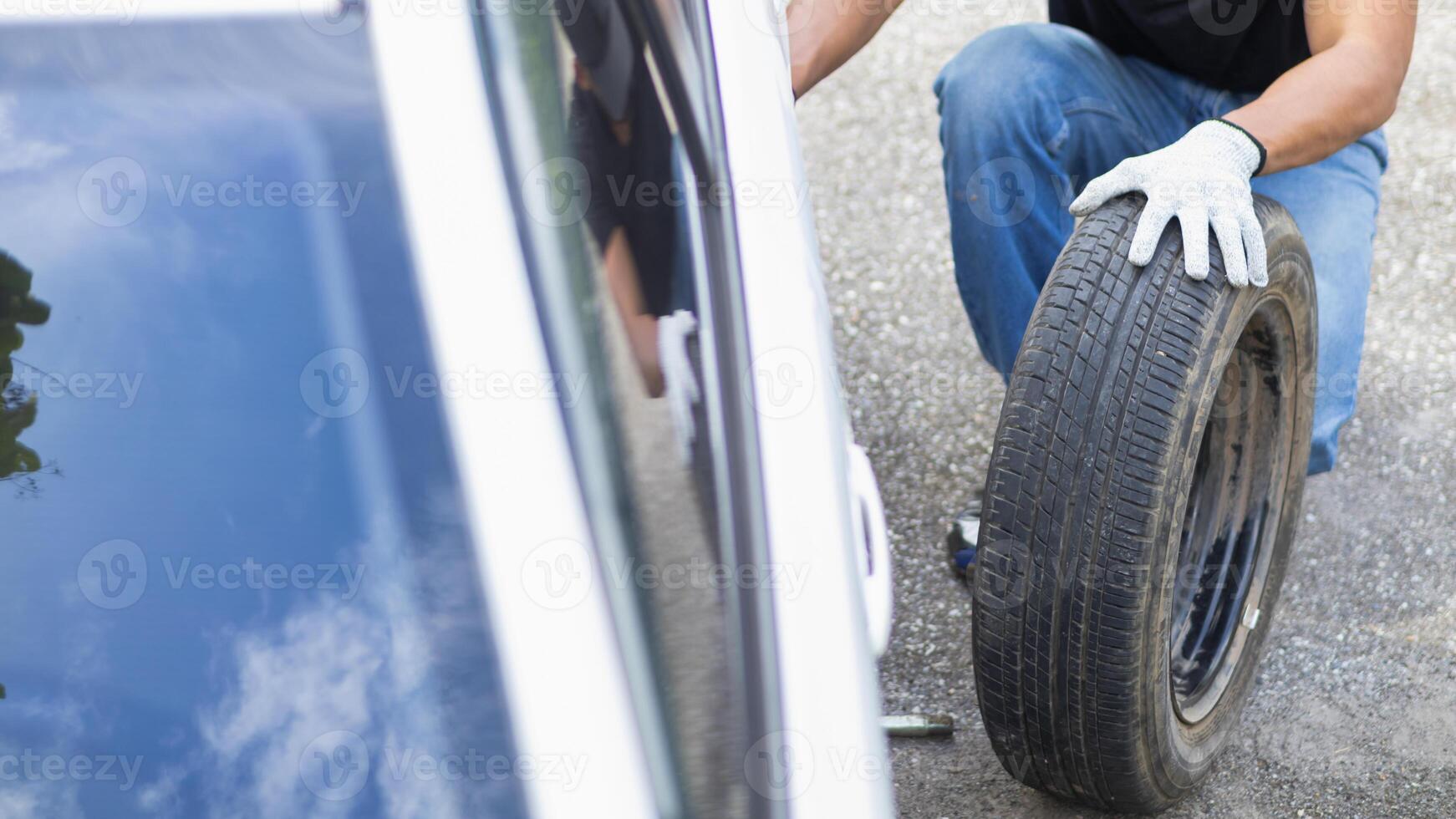 mechanic is preparing the equipment and spare tire to change the tire of the car that had a flat tire during the journey and the mechanic was called by the emergency application of the service center. photo