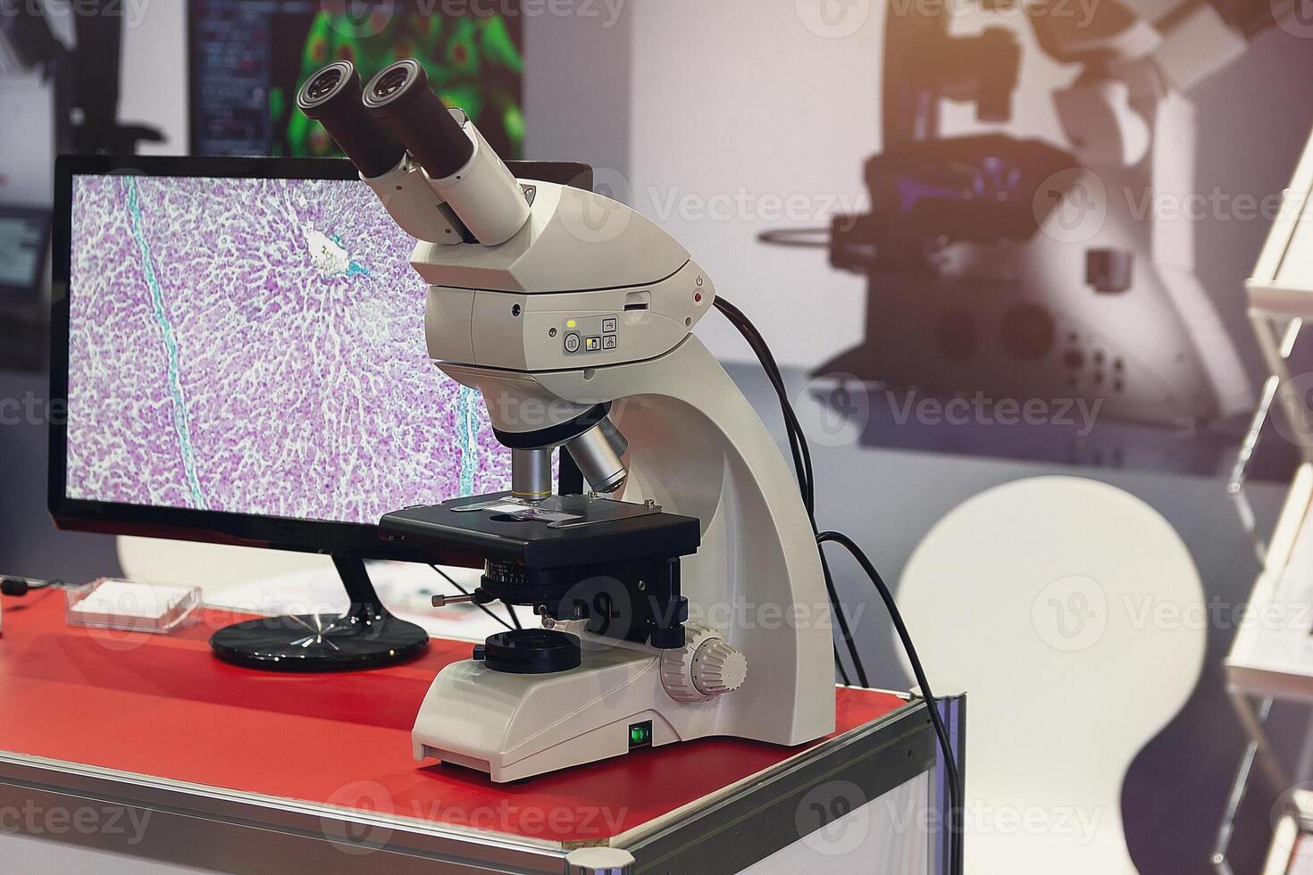 Modern microscope and slide section of human tissue with computer monitor photo