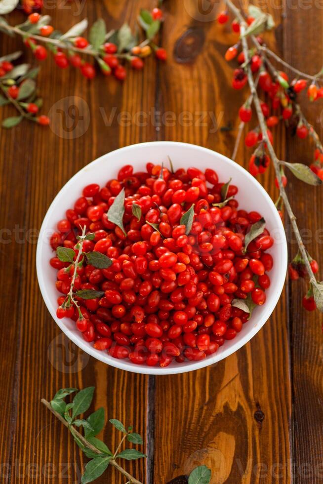 fresh ripe red goji berries in a bowl on a wooden table photo