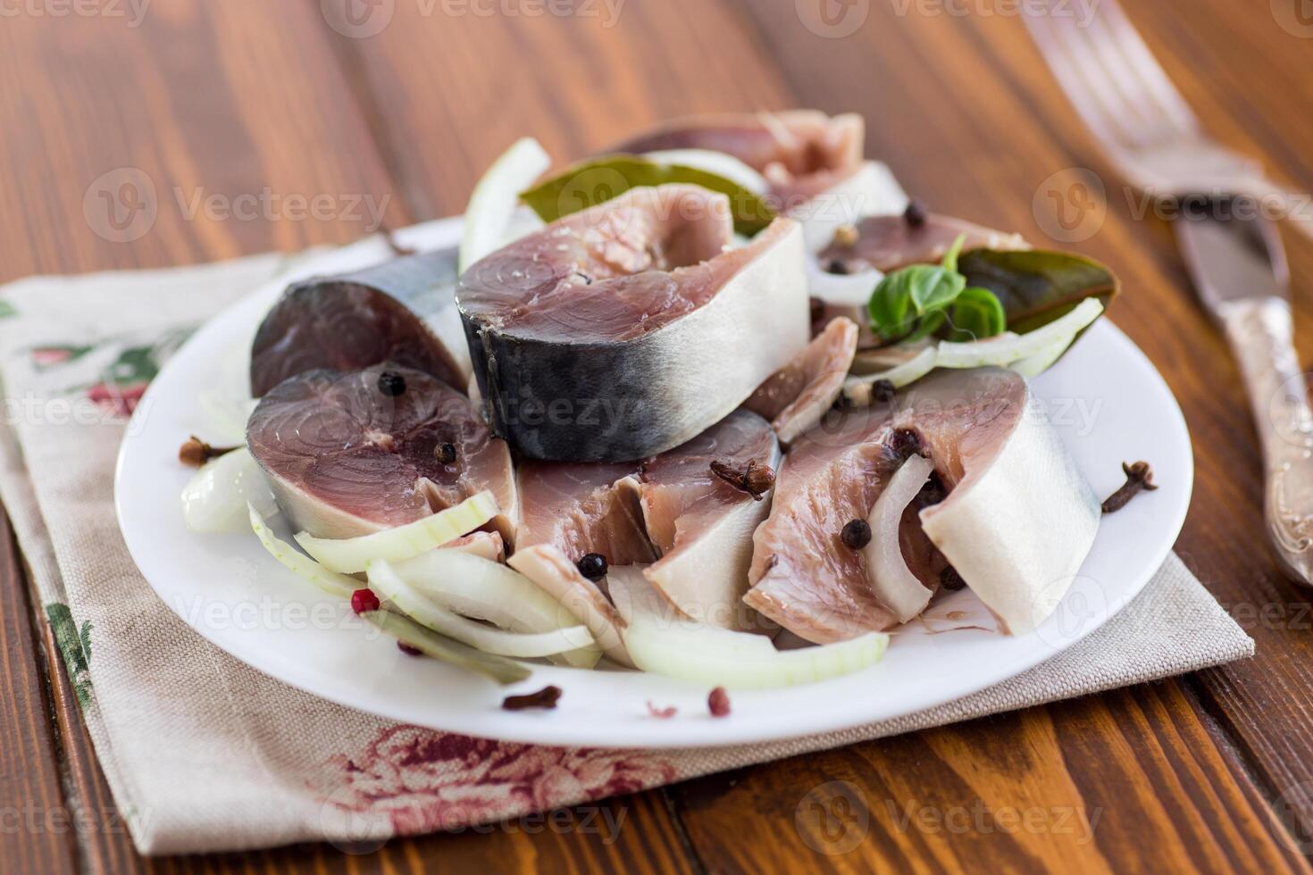 lightly salted mackerel with onions and spices on a wooden table photo