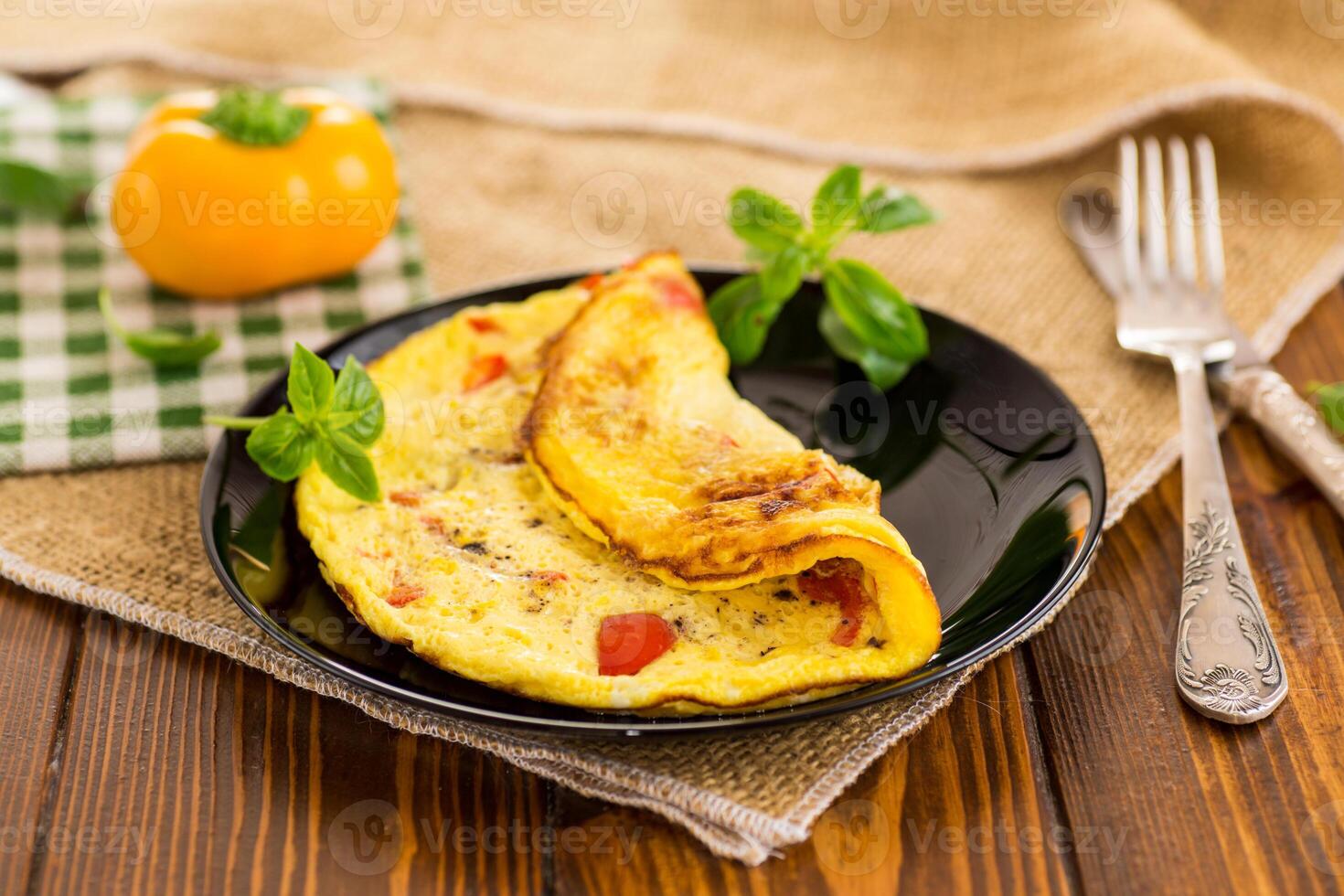 fried omelette with sweet pepper and vegetables in a plate on a wooden table photo