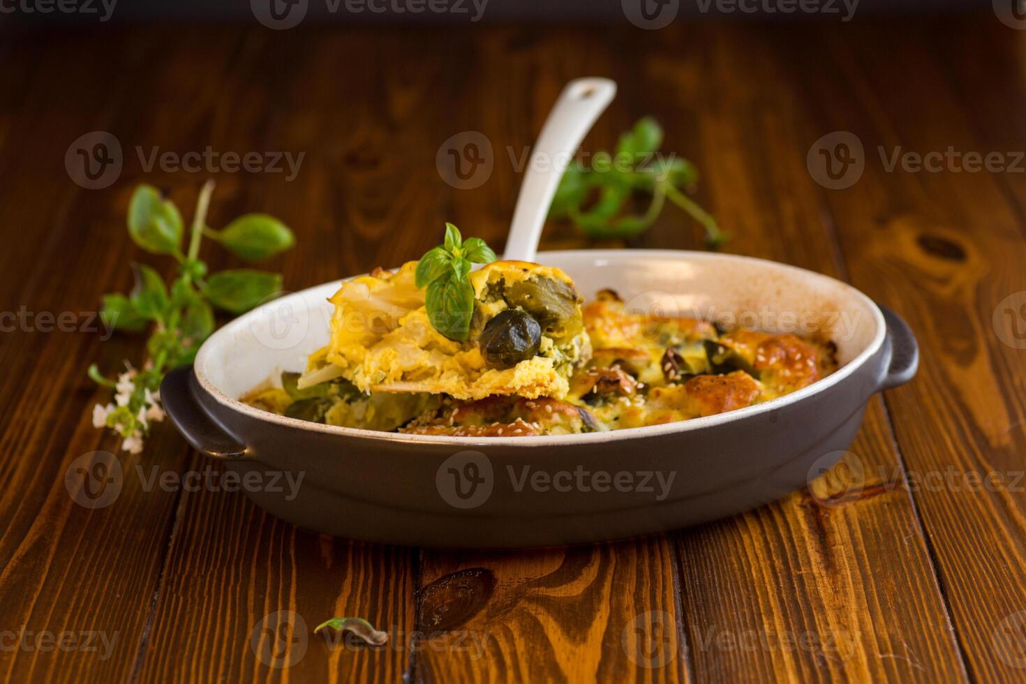 cauliflower and brussels sprouts casserole with cheese, in a ceramic dish on a wooden table photo
