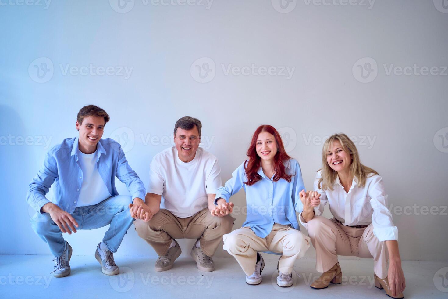 a family, middle-aged husband and wife, young adult son and teenage daughter, squatting on a white background, studio photo shoot