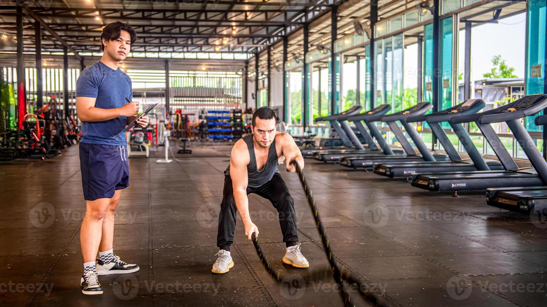 Male trainer testing his trainee's physical abilities. With a rope swing at the fitness center photo