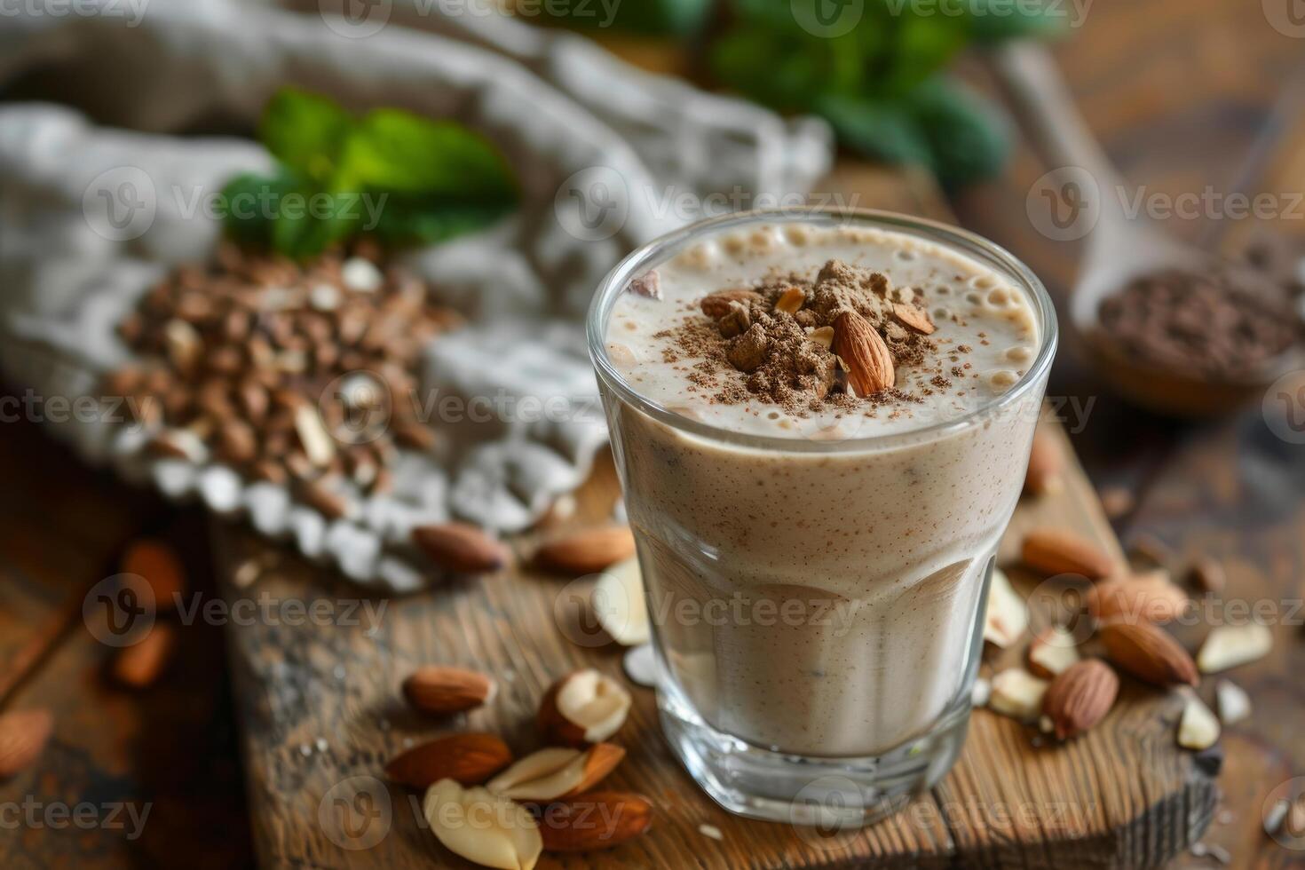 Protein shake standing on wooden table surrounded by almonds and cocoa powder photo