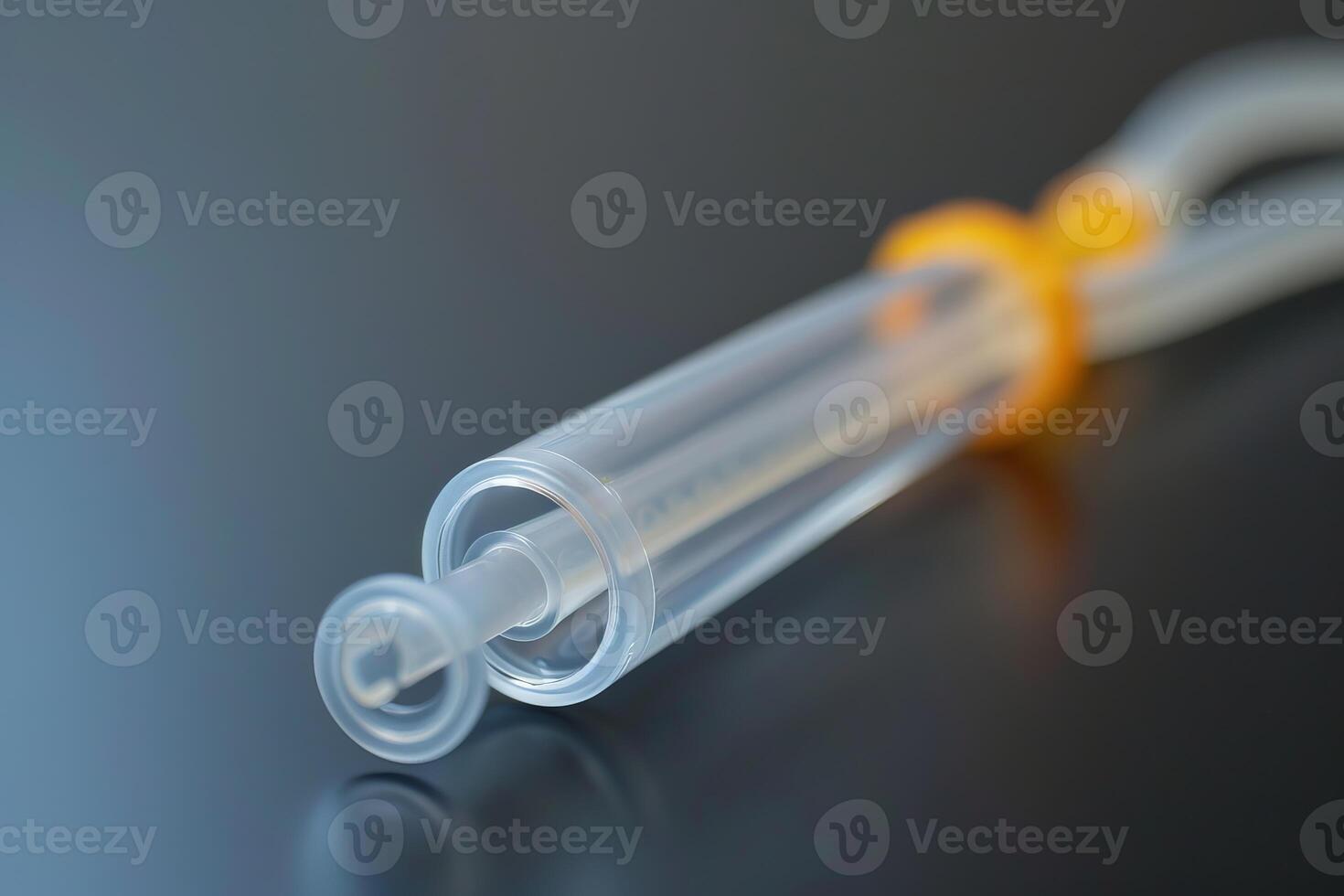 Close up of syringe with orange clamp lying on dark reflective surface photo