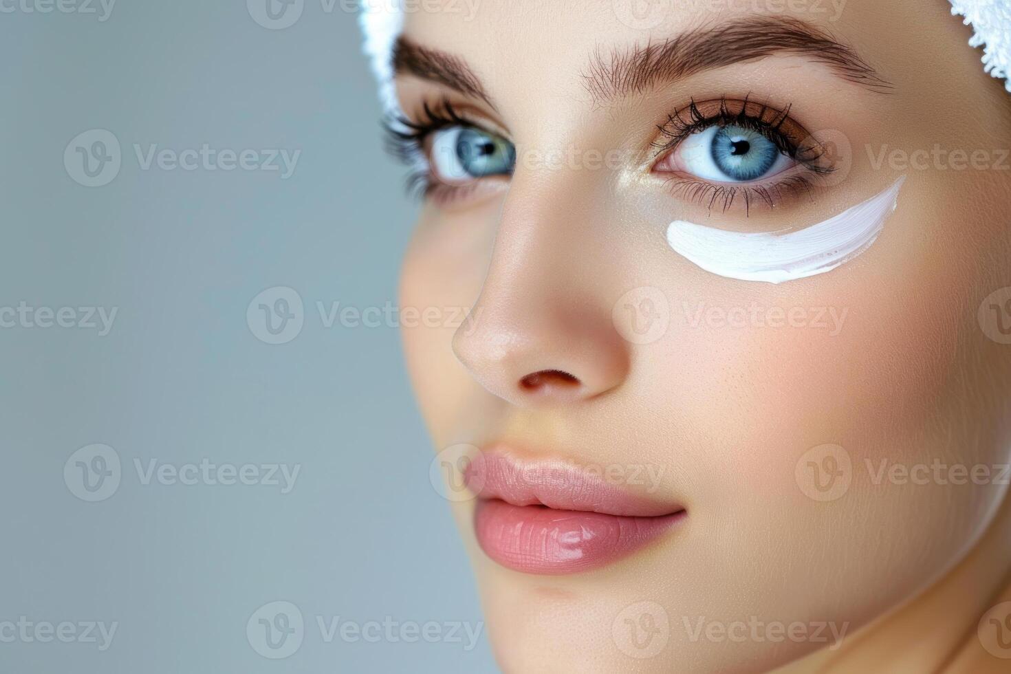 Beautiful young woman applying eye cream under eye photo