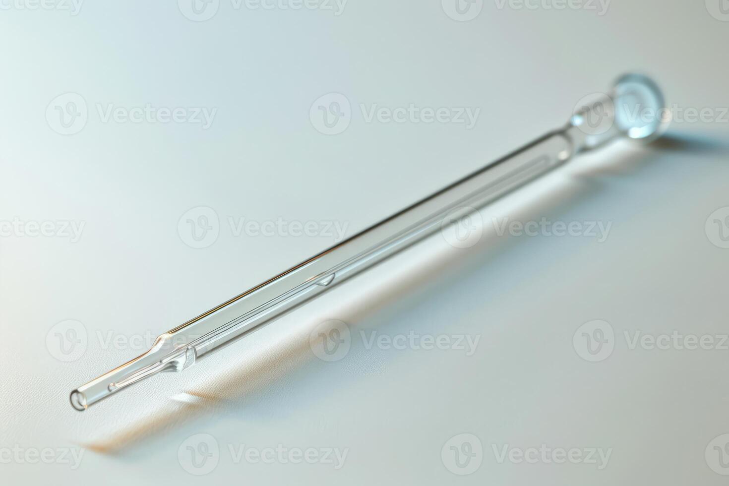 Empty glass pipette lying on a white surface photo
