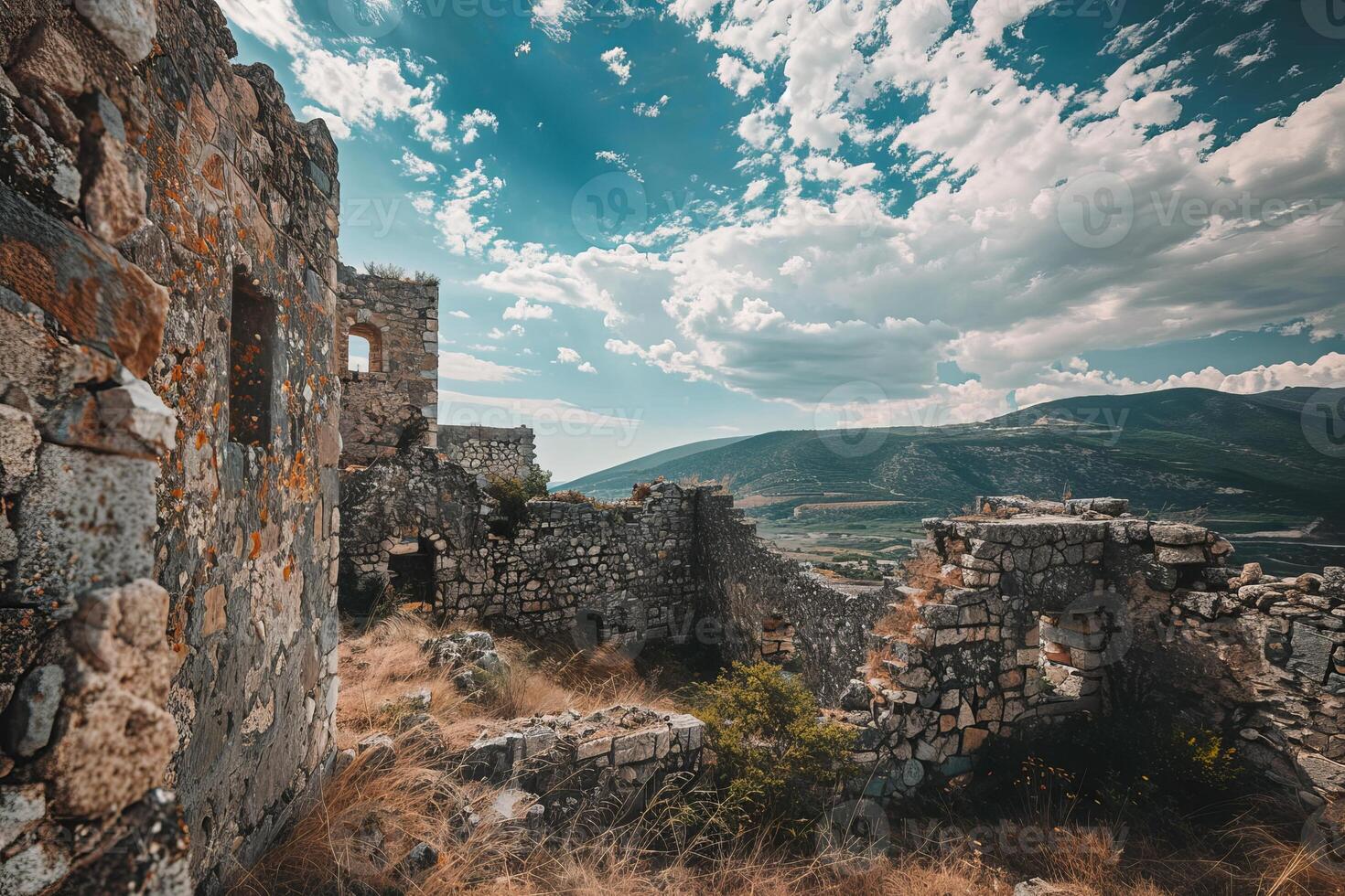 Ruins of ancient stone building standing on hill overlooking valley photo