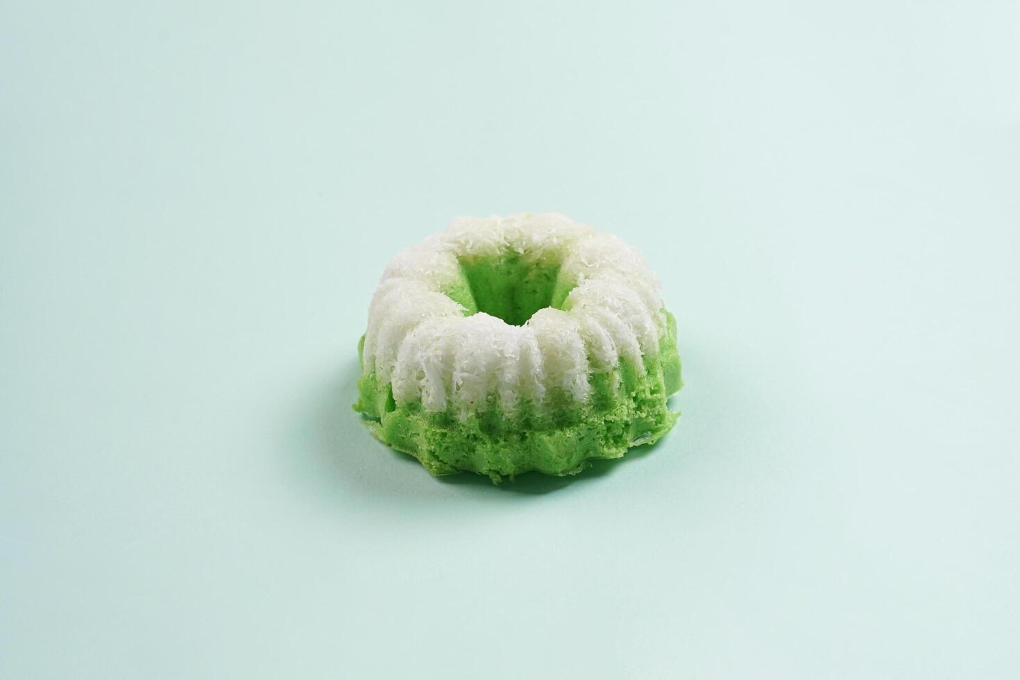 Putu ayu isolated on green background. It is a traditional dessert made from steamed rice flour and topped with grated coconut, a classic Indonesian cake photo