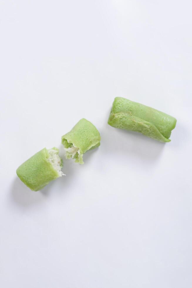 Traditional Indonesian food called 'Dadar Gulung', an elliptical cake filled with grated coconut and liquid palm sugar, isolated on a white background. photo