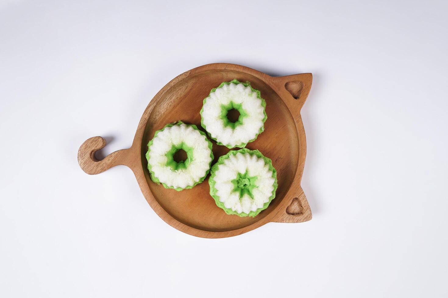 Putu Ayu is served on a wooden plate with white background. It is a traditional dessert made from steamed rice flour and topped with grated coconut, a classic Indonesian cake photo