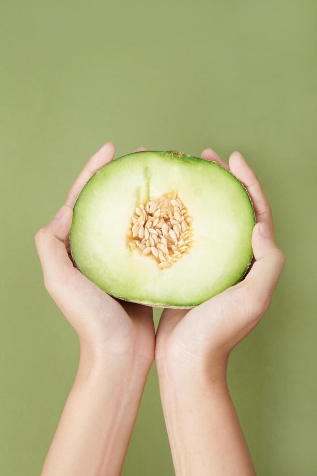 hand holding sliced green cantaloupe melon isolated on green background, green melon photo