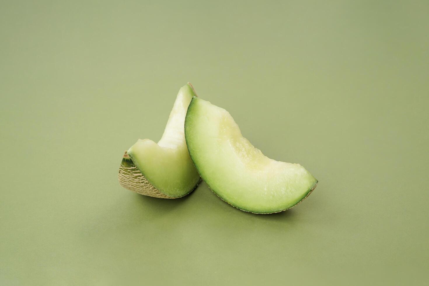 Green cantaloupe melon with cut slice isolated on green background, green melon photo