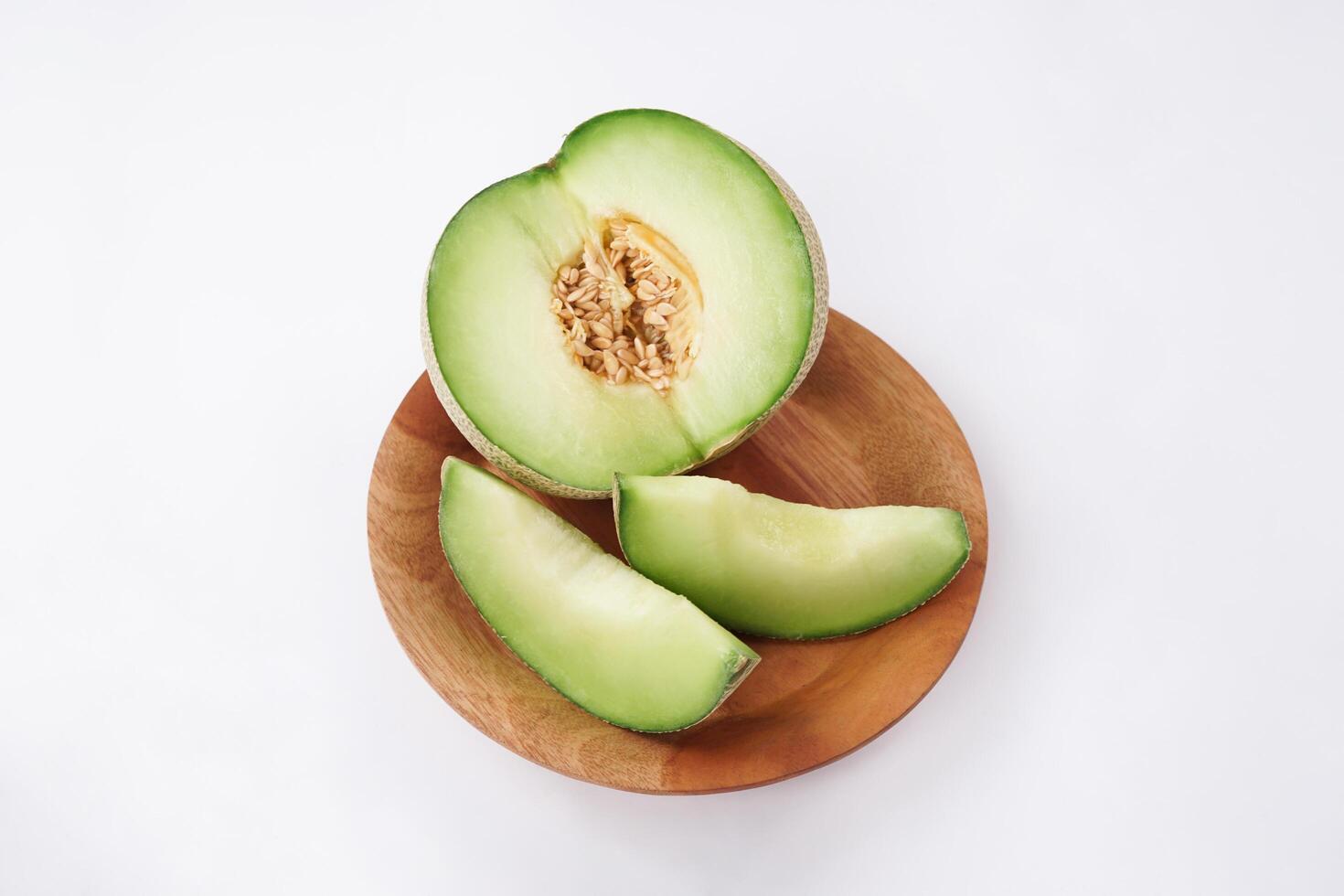 Green cantaloupe melon slice in wooden bowl isolated on white background, green melon photo