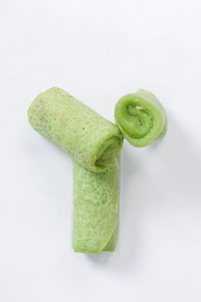 Traditional Indonesian food called 'Dadar Gulung', an elliptical cake filled with grated coconut and liquid palm sugar, isolated on a white background. photo