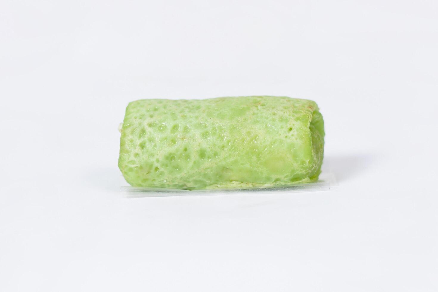 Traditional Indonesian food called 'Dadar Gulung', an elliptical cake filled with grated coconut and liquid palm sugar, isolated on a white background. photo