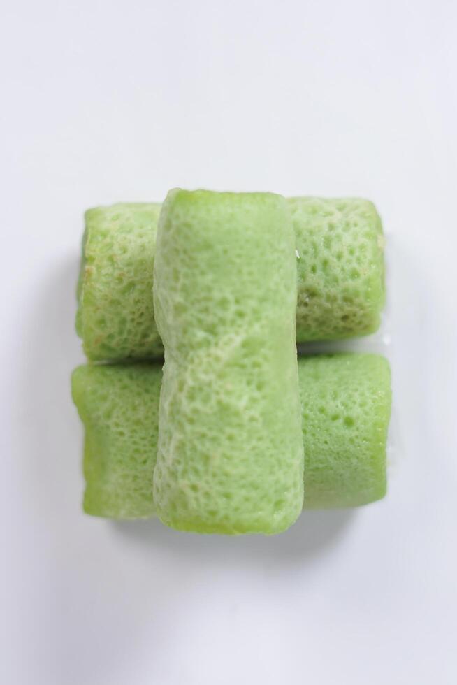 Traditional Indonesian food called 'Dadar Gulung', an elliptical cake filled with grated coconut and liquid palm sugar, isolated on a white background. photo