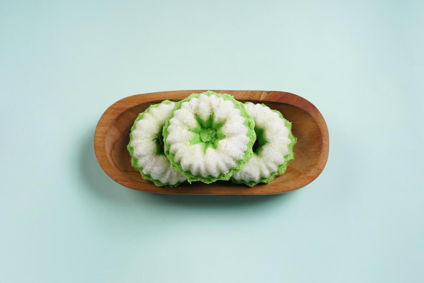 Putu Ayu is served on a wooden plate with green background. It is a traditional dessert made from steamed rice flour and topped with grated coconut, a classic Indonesian cake photo