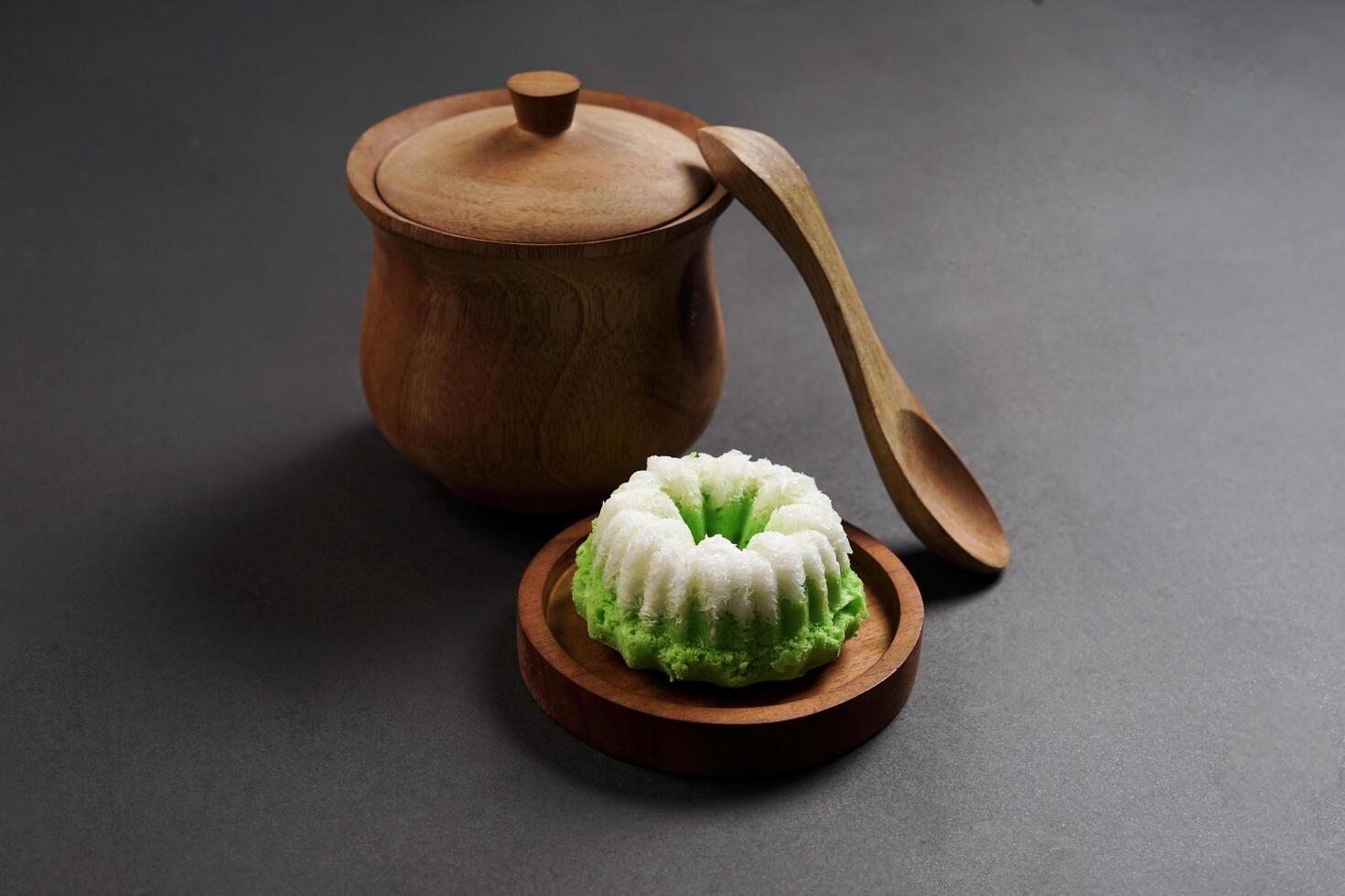 Putu Ayu is served on a wooden plate with a dark background. It is a traditional dessert made from steamed rice flour and topped with grated coconut, a classic Indonesian cake photo