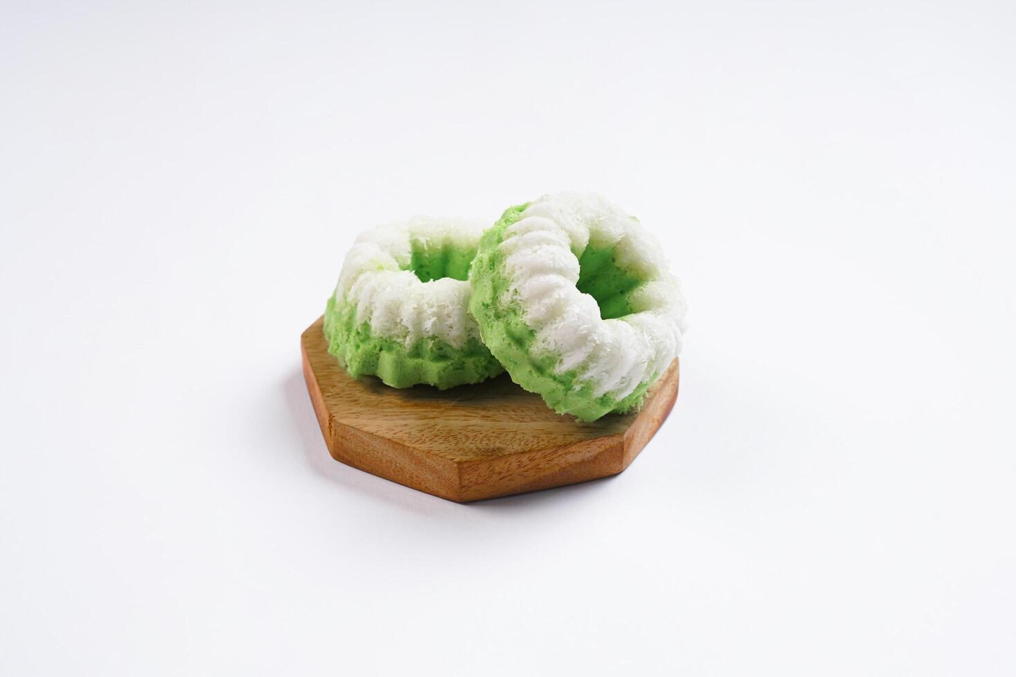 Putu Ayu is served on a wooden plate with white background. It is a traditional dessert made from steamed rice flour and topped with grated coconut, a classic Indonesian cake photo