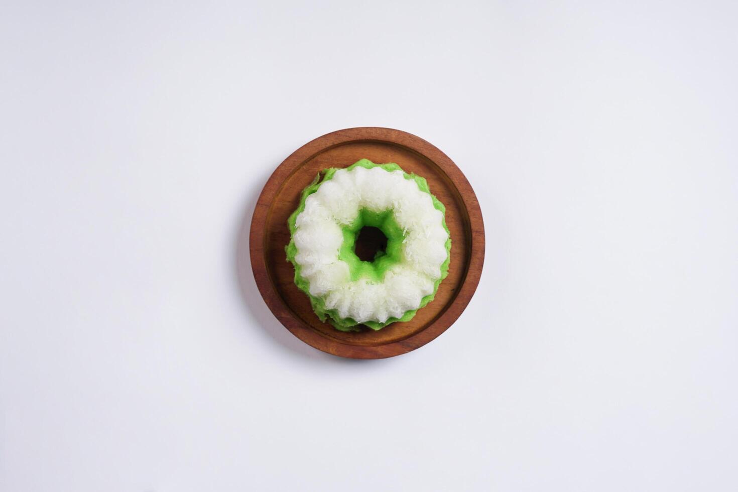 Putu Ayu is served on a wooden plate with white background. It is a traditional dessert made from steamed rice flour and topped with grated coconut, a classic Indonesian cake photo
