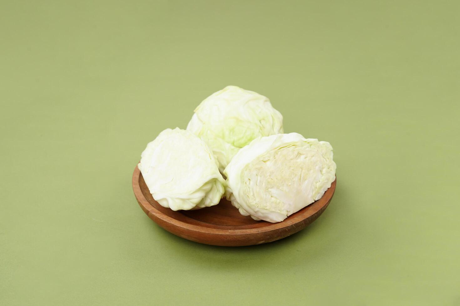 Green cabbage on a wooden plate, isolated against a green background photo