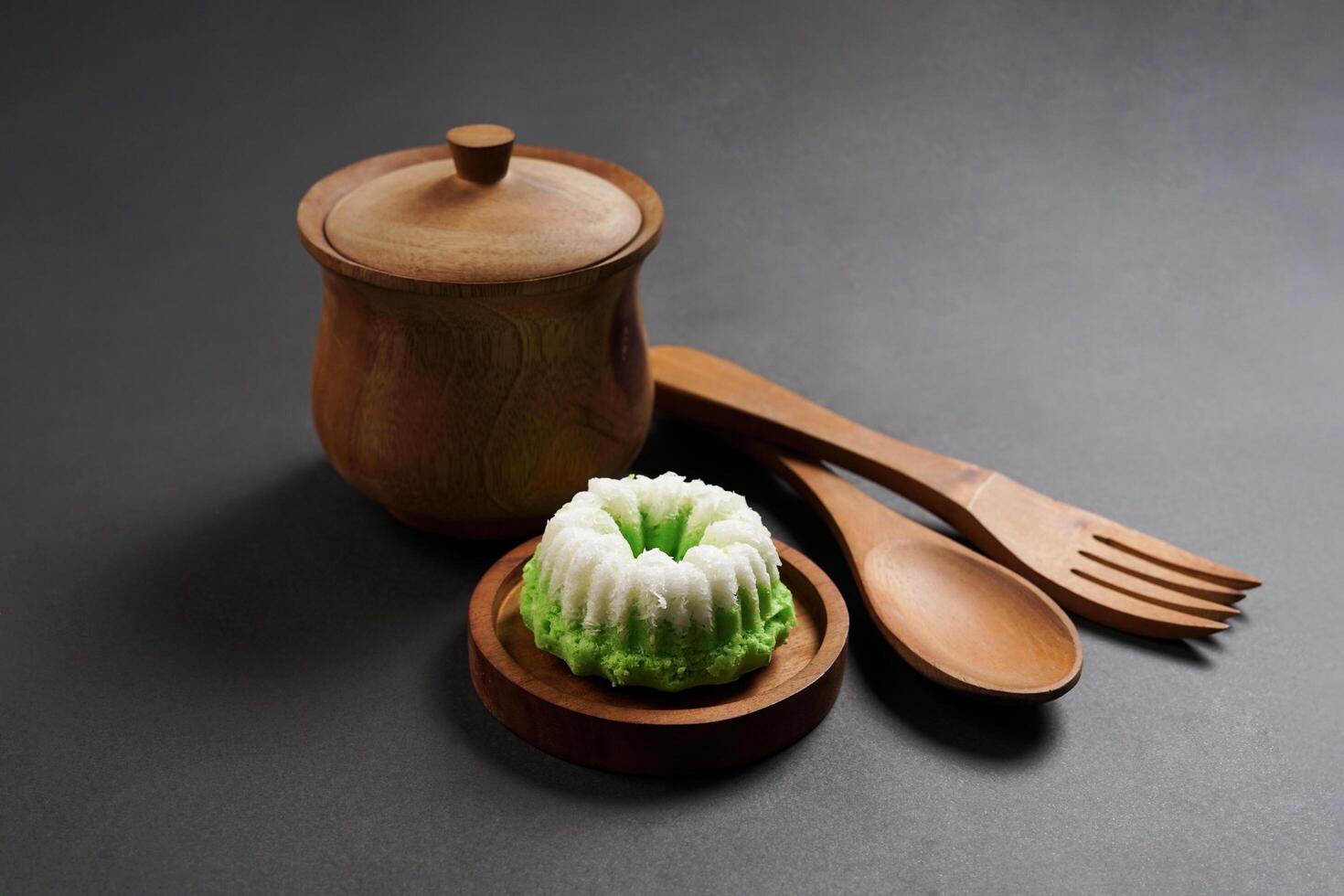 Putu Ayu is served on a wooden plate with a dark background. It is a traditional dessert made from steamed rice flour and topped with grated coconut, a classic Indonesian cake photo