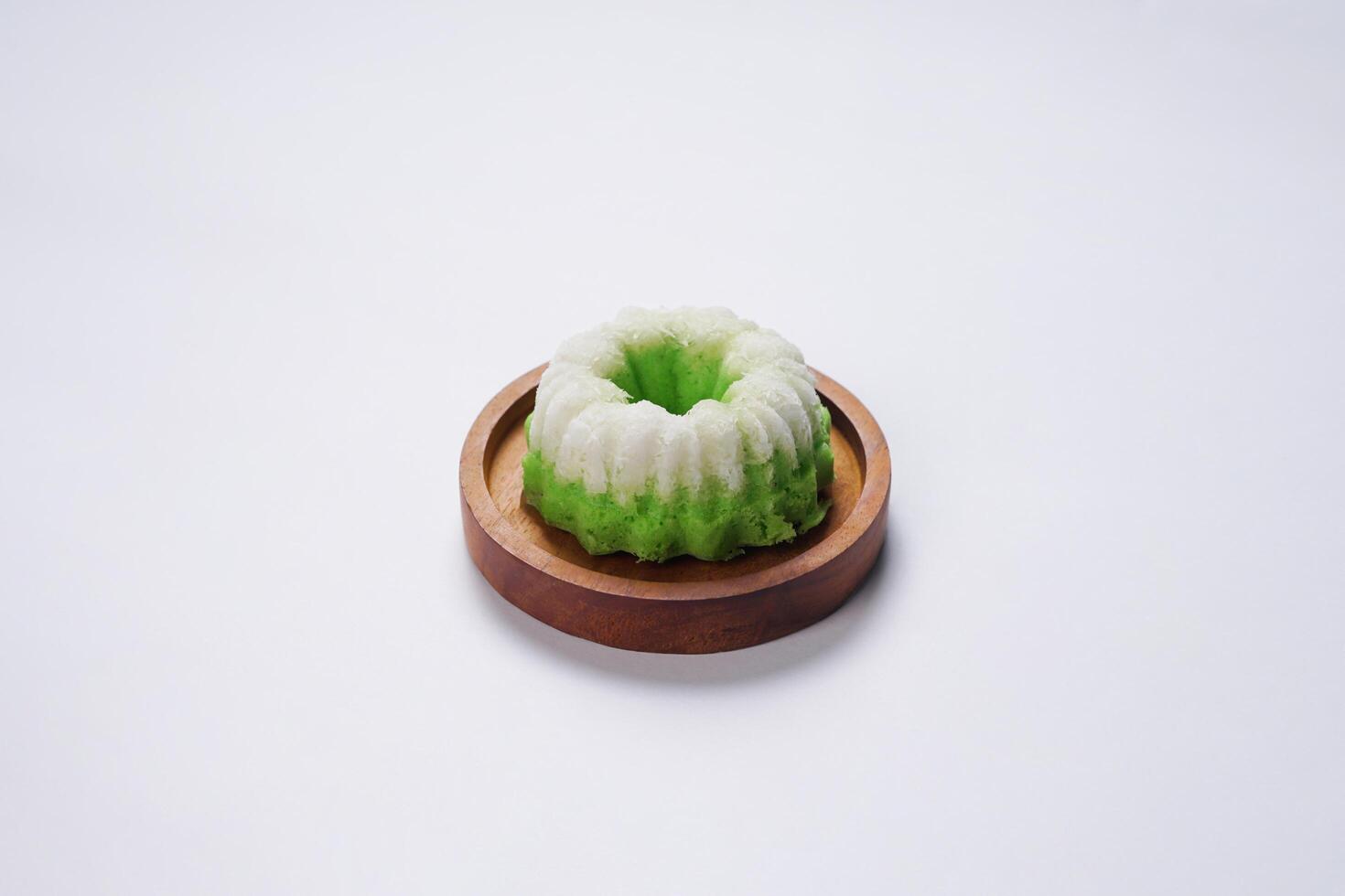 Putu Ayu is served on a wooden plate with white background. It is a traditional dessert made from steamed rice flour and topped with grated coconut, a classic Indonesian cake photo