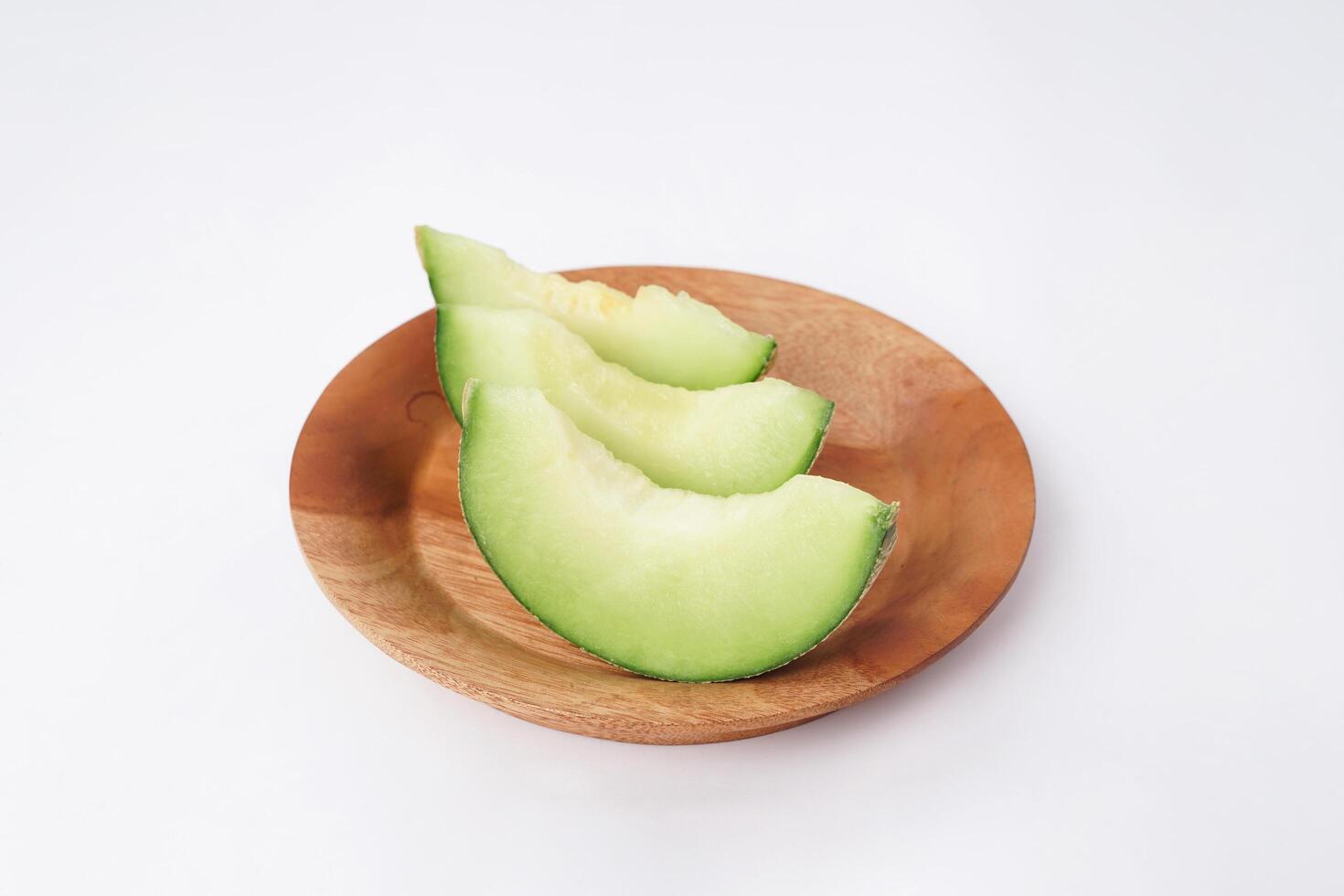 Green cantaloupe melon slice in wooden bowl isolated on white background, green melon photo