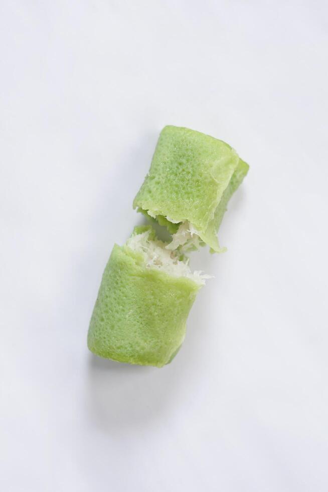 Traditional Indonesian food called 'Dadar Gulung', an elliptical cake filled with grated coconut and liquid palm sugar, isolated on a white background. photo