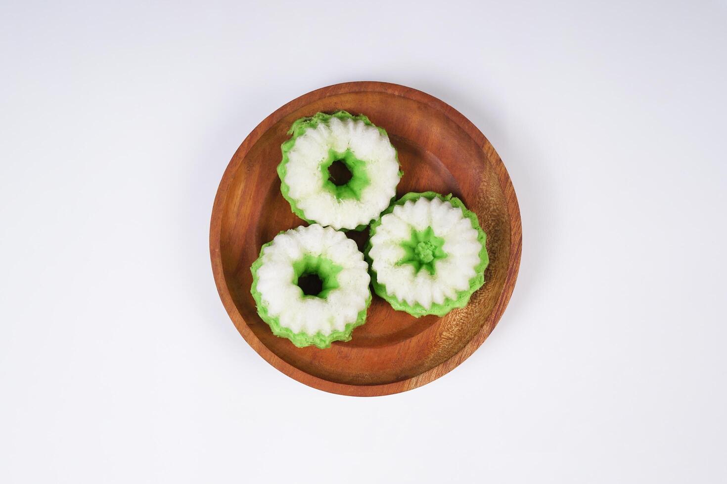 Putu Ayu is served on a wooden plate with white background. It is a traditional dessert made from steamed rice flour and topped with grated coconut, a classic Indonesian cake photo