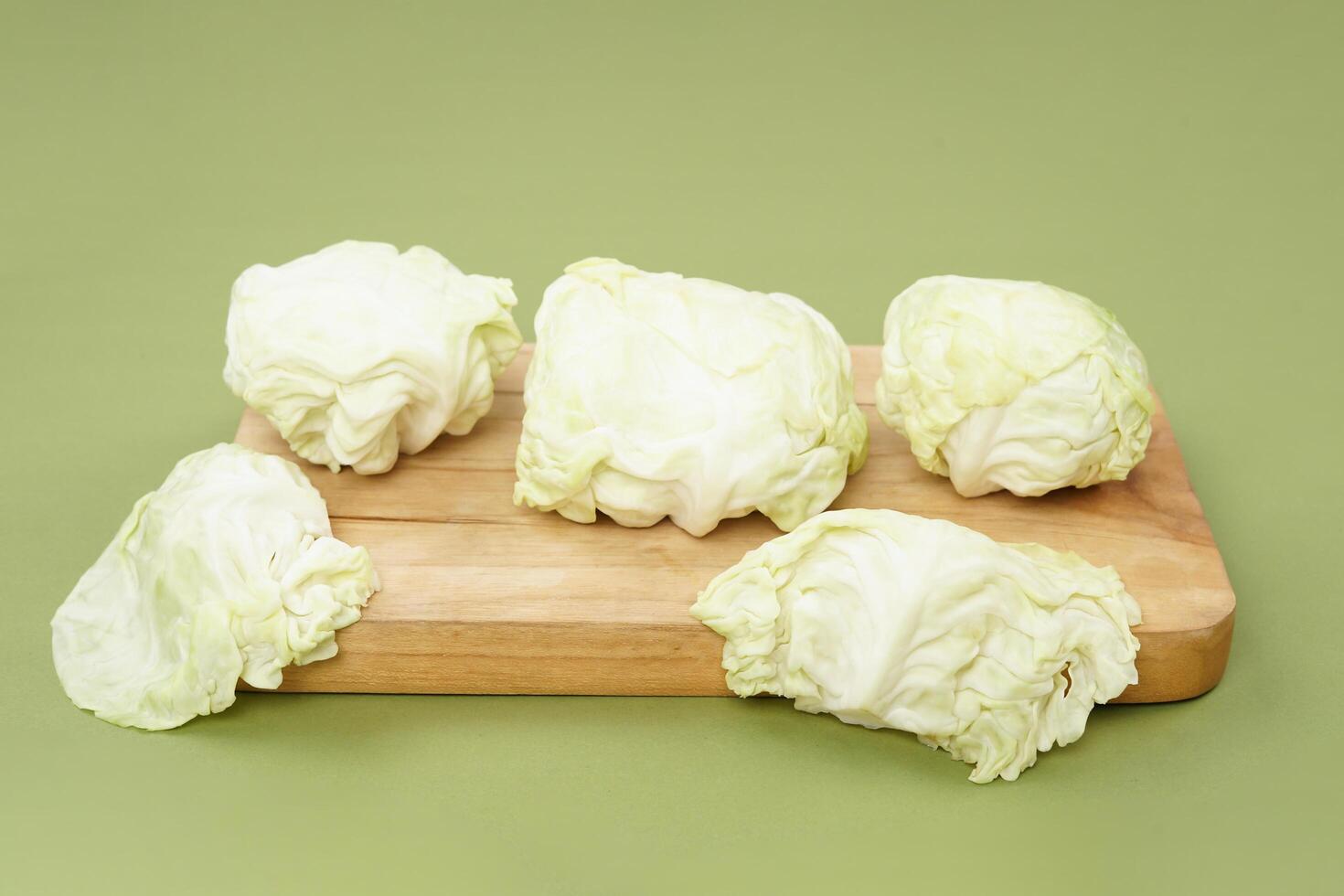 Green cabbage on a wooden plate, isolated against a green background photo