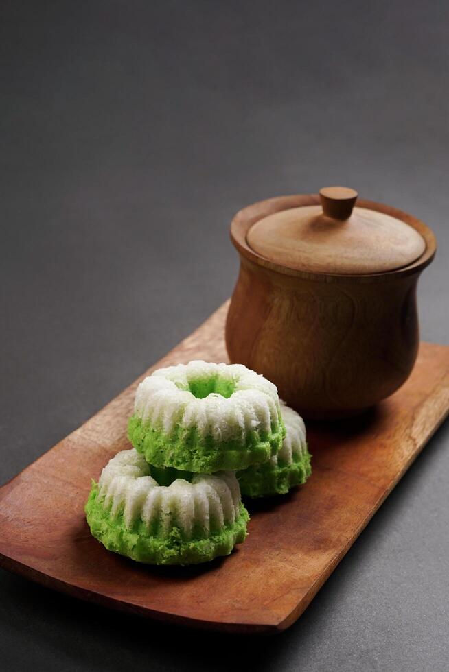 Putu Ayu is served on a wooden plate with a dark background. It is a traditional dessert made from steamed rice flour and topped with grated coconut, a classic Indonesian cake photo