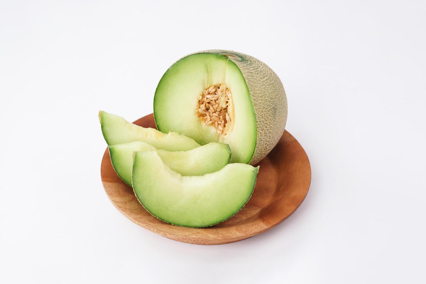 Green cantaloupe melon slice in wooden bowl isolated on white background, green melon photo