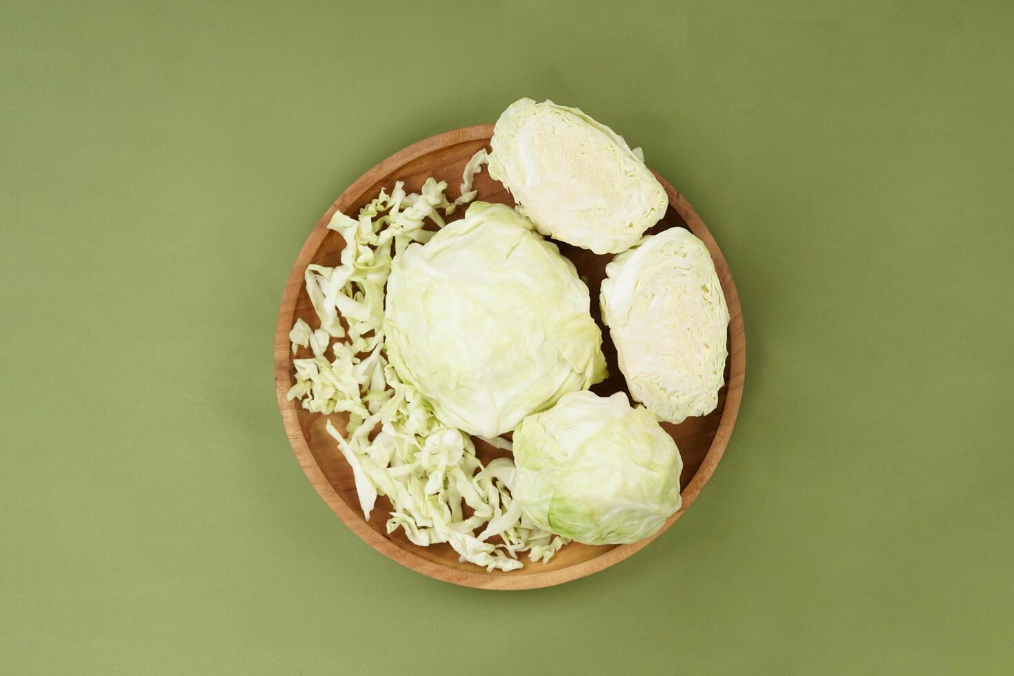 Green cabbage on a wooden plate, isolated against a green background, top view photo