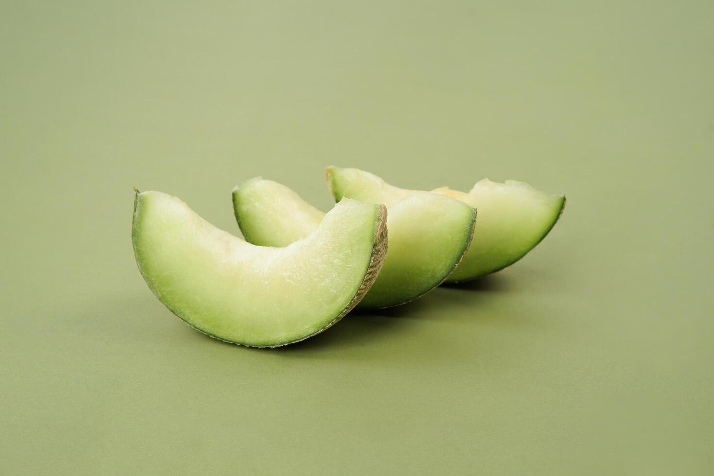 Green cantaloupe melon with cut slice isolated on green background, green melon photo