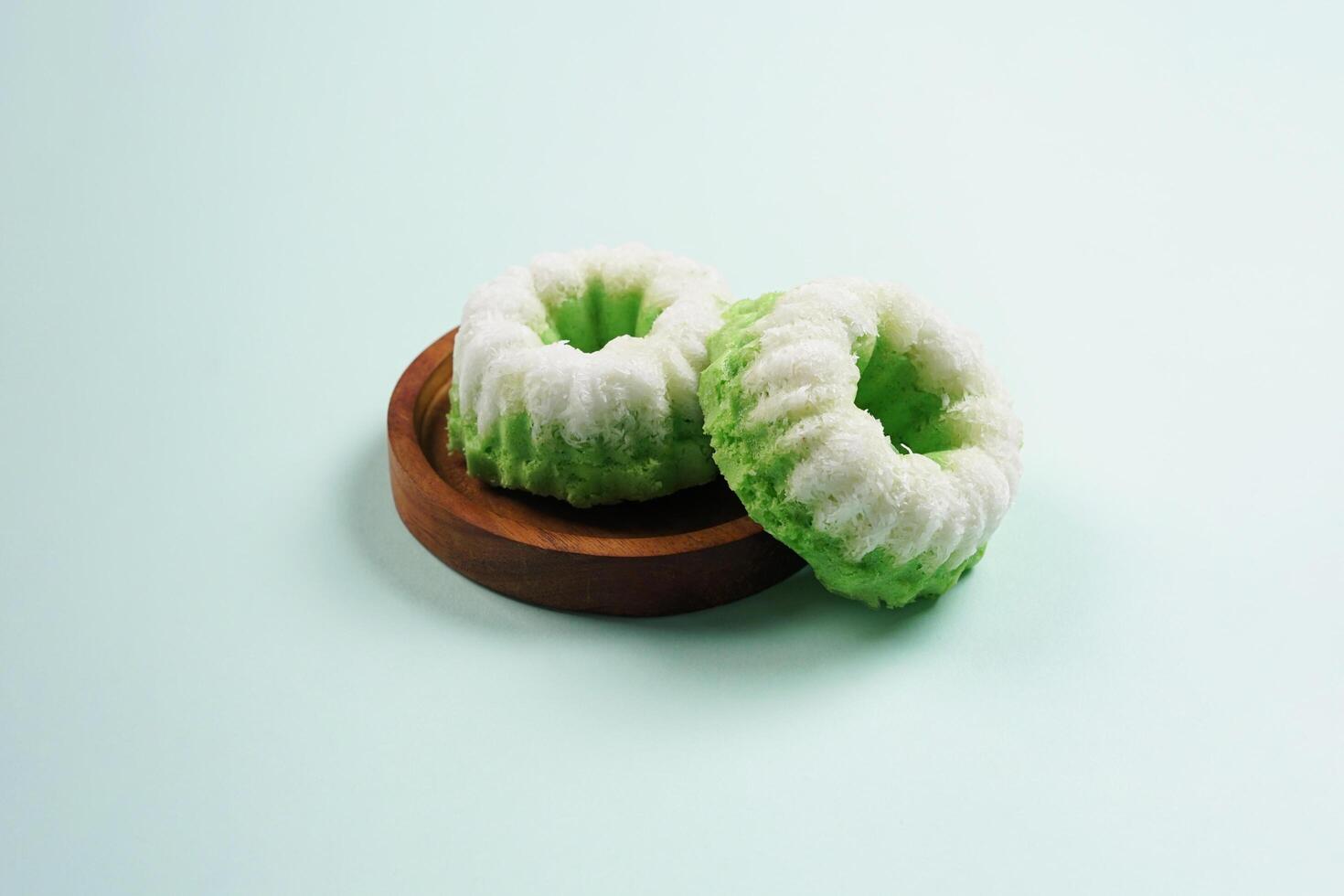 Putu Ayu is served on a wooden plate with green background. It is a traditional dessert made from steamed rice flour and topped with grated coconut, a classic Indonesian cake photo
