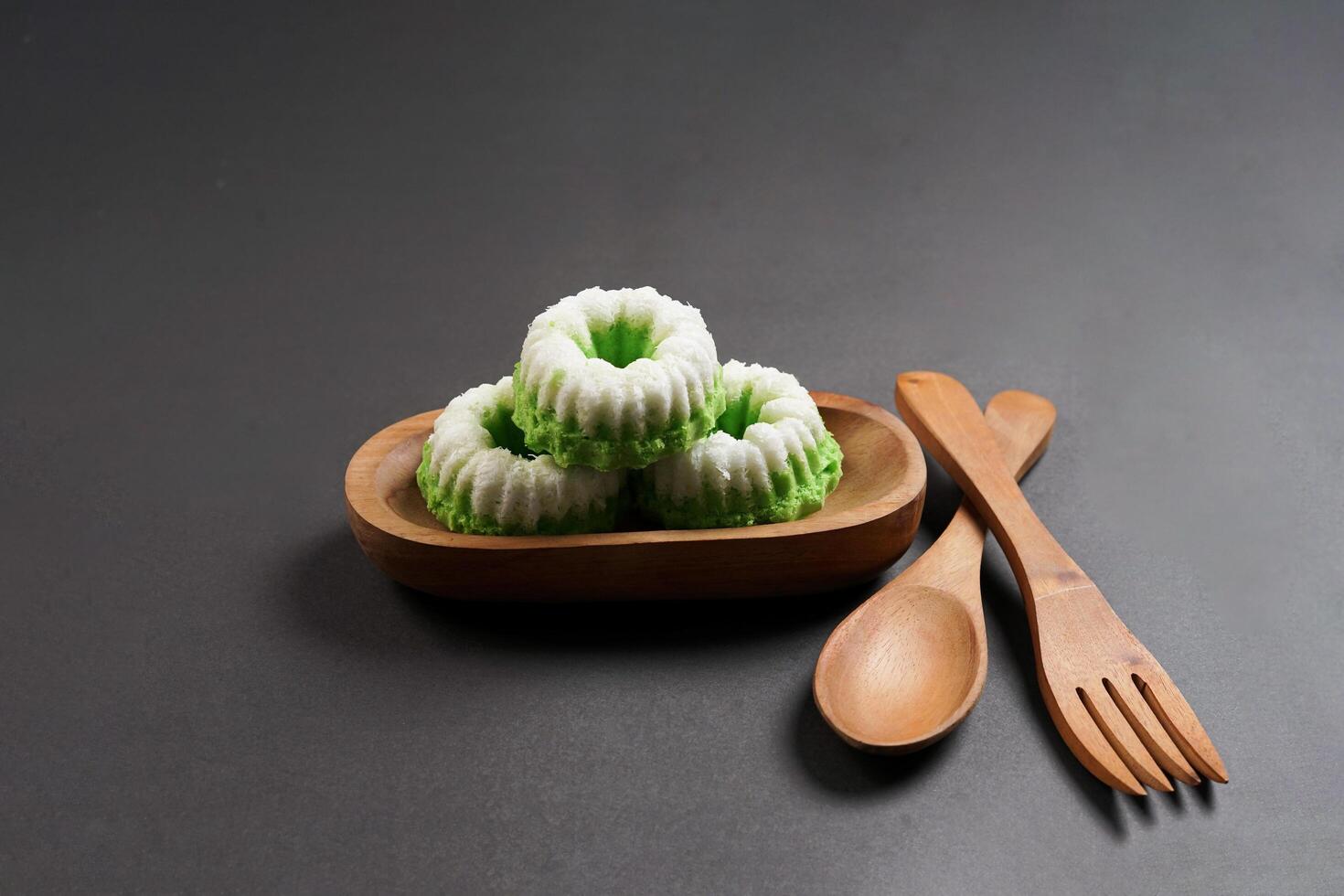 Putu Ayu is served on a wooden plate with a dark background. It is a traditional dessert made from steamed rice flour and topped with grated coconut, a classic Indonesian cake photo