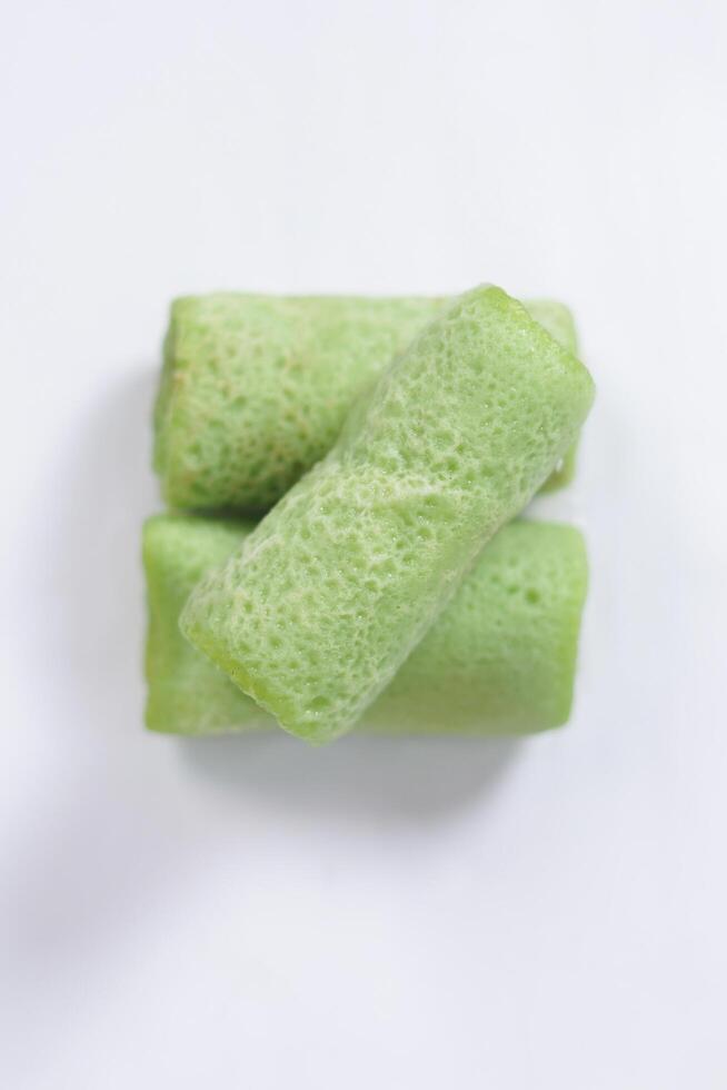 Traditional Indonesian food called 'Dadar Gulung', an elliptical cake filled with grated coconut and liquid palm sugar, isolated on a white background. photo