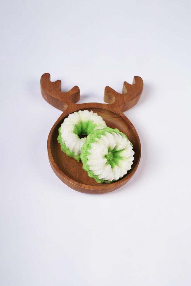 Putu Ayu is served on a wooden plate with white background. It is a traditional dessert made from steamed rice flour and topped with grated coconut, a classic Indonesian cake photo