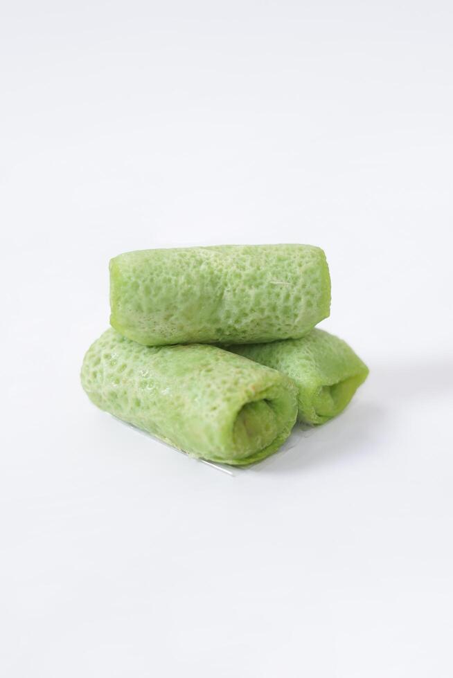 Traditional Indonesian food called 'Dadar Gulung', an elliptical cake filled with grated coconut and liquid palm sugar, isolated on a white background. photo
