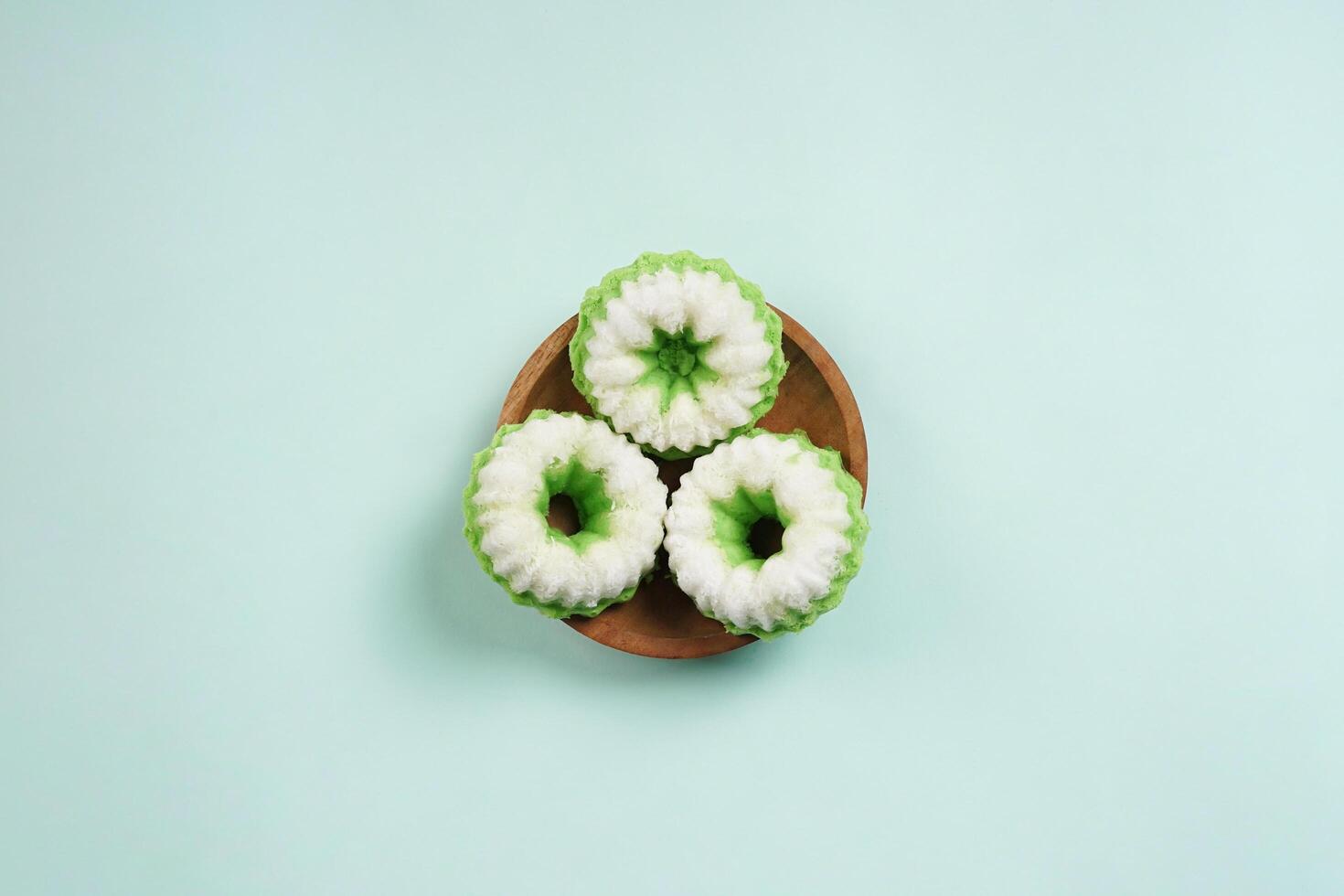 Putu Ayu is served on a wooden plate with green background. It is a traditional dessert made from steamed rice flour and topped with grated coconut, a classic Indonesian cake photo