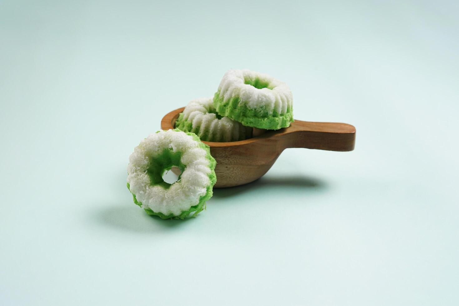 Putu Ayu is served on a wooden plate with green background. It is a traditional dessert made from steamed rice flour and topped with grated coconut, a classic Indonesian cake photo