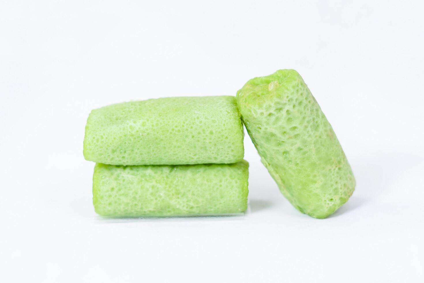 Traditional Indonesian food called 'Dadar Gulung', an elliptical cake filled with grated coconut and liquid palm sugar, isolated on a white background. photo