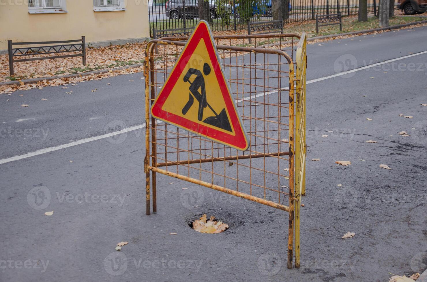 Road Repair sign. On the asphalt, the pit is fenced and there is a sign photo