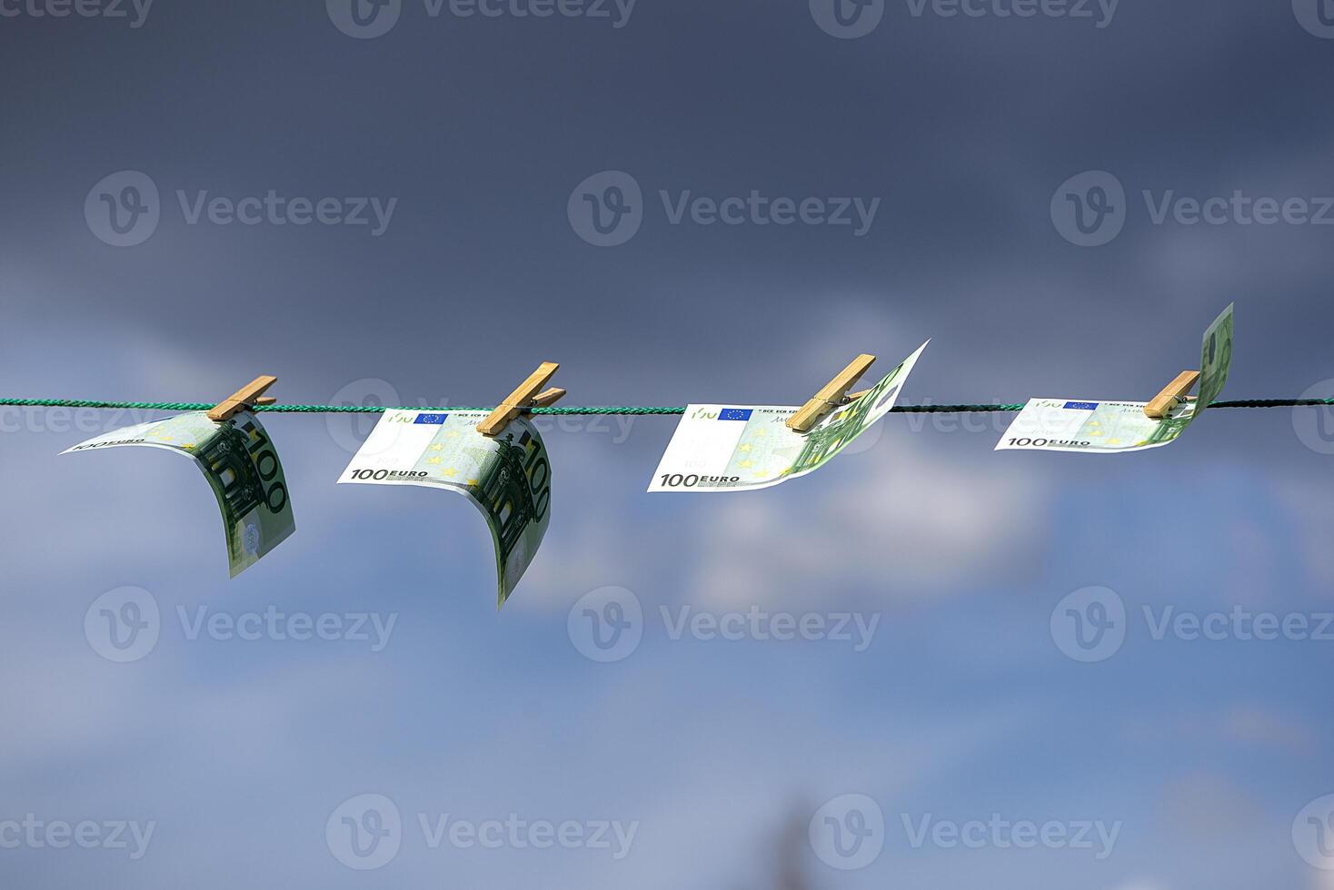 Euro banknotes on a rope. Cash laundry concept on a blue sky background. Clean money hung out to dry. EUR banknotes hanging on a string against blue background. Euro paper money on the rope. photo
