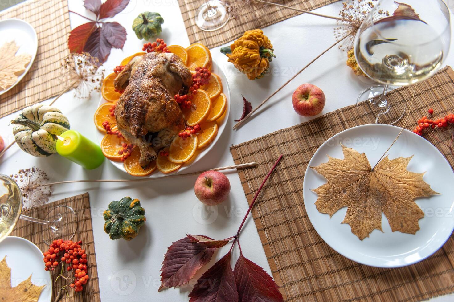 Thanksgiving table setting with automnal decorations, pumpkins, glasses and plates. photo