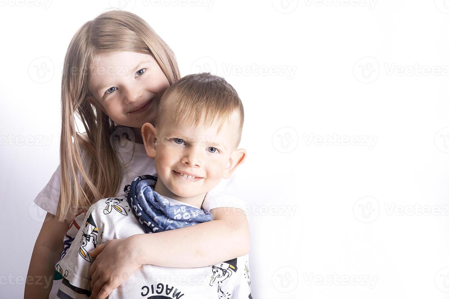 Two happy little children - sister and brother smile and hug on a light white background photo