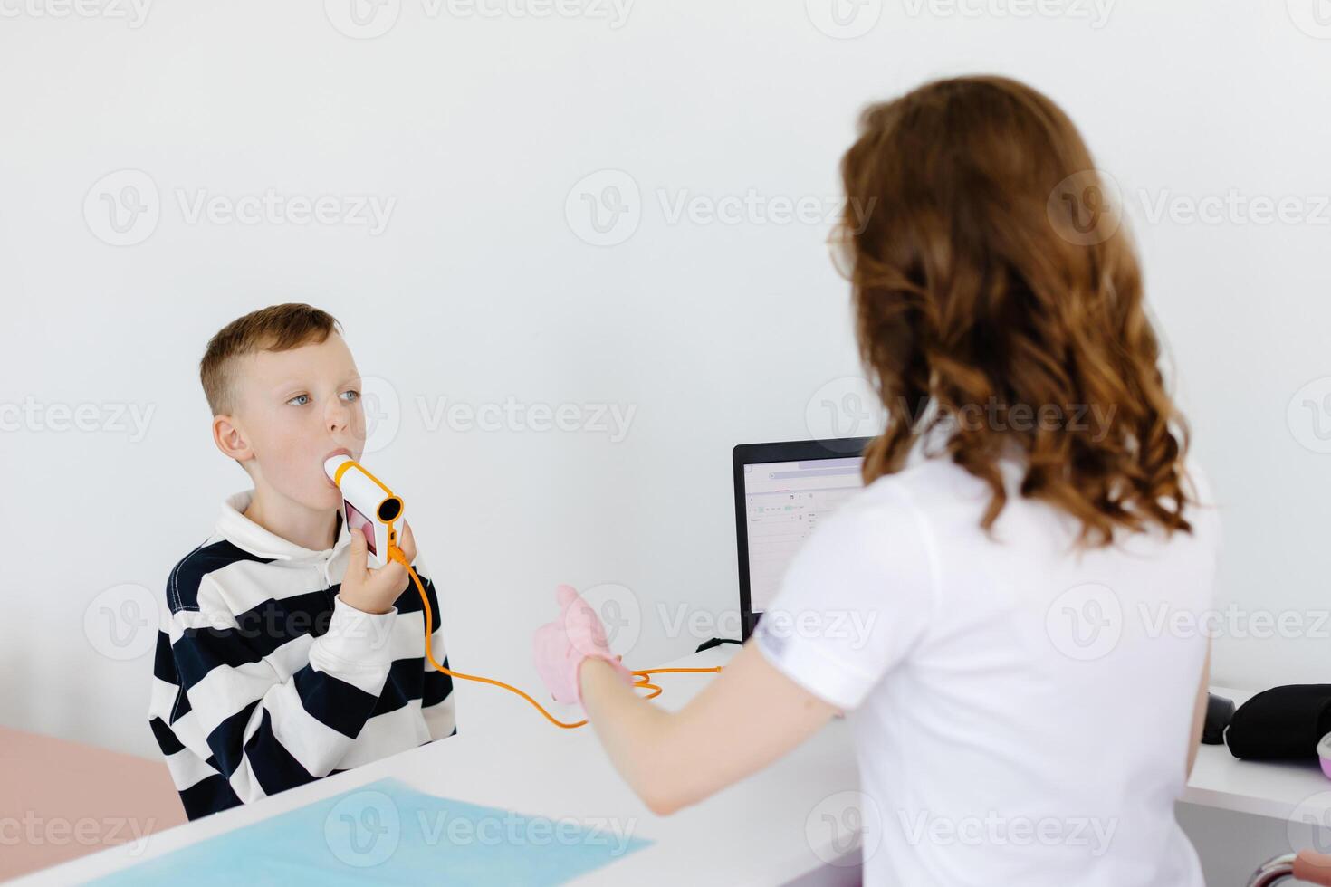 Boy testing breathing function by spirometry in doctors office. Diagnosis of respiratory function in pulmonary disease photo
